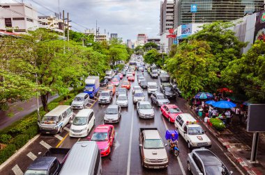 Bangkok, Tayland - 11 Temmuz 2015: Tayland 'ın başkenti Bangkok' ta trafik yoğun, arabalar, otobüsler, taksiler ve yeşil ağaçlarla çevrili geniş sokaktaki insanlar