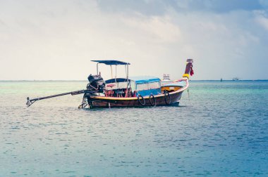 Geleneksel ahşap Tayland teknesi okyanusun ortasında ve arka planda bulutlu bir gökyüzü var.