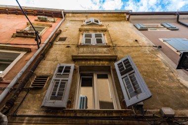 Eski bir binanın birinci katında beyaz kepenkler açıldı.