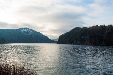 Ormanla kaplı dağların arasındaki gölde gün batımı