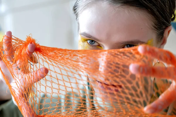 Girl with an orange mesh on her face.