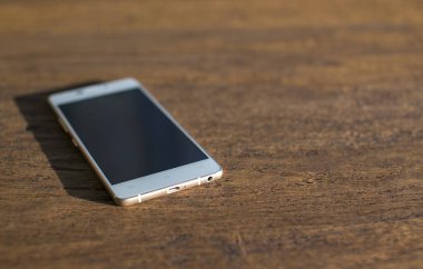 Ahşap bir masa beyaz telefonda. yakın çekim