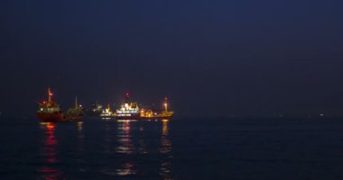 Balıkçı teknesi ve kargo gemileri gün batımında. Istanbul, Türkiye. Zaman atlamalı.