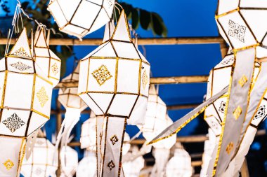 Geceleri bambu bardan sarkan beyaz Çin fenerlerinin resmi.