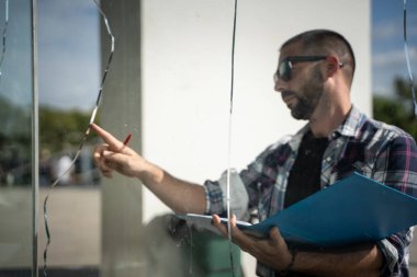 Sigorta şirketinin evindeki kırık camları kontrol eden adam..