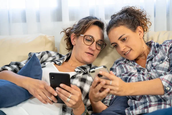 Ellerinde cep telefonlarıyla kanepede yatan iki kızın bilgilerini paylaşırken çekilmiş bir fotoğraf.