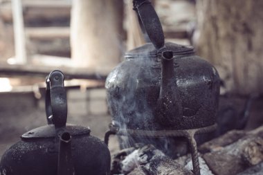Tayland 'da duman yükselirken, odun ateşinde siyah çaydanlık ısınıyor.