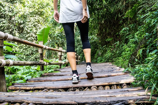 legs of a girl in tights walking on an old wooden bridge in the middle of the forest in northern Thailand
