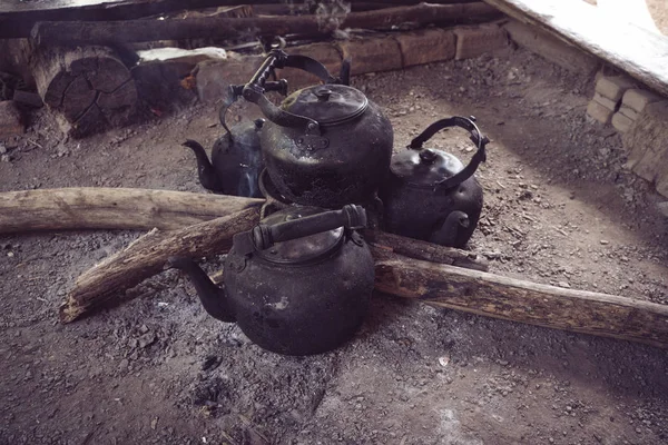 black teapots on the floor with burnt wood and ashes in Thailand
