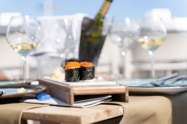 Balık yumurtalarından oluşan suşi yiyeceği, açık hava restoranının terasında şarap bardakları ve bir şişe şarapla küçük bir masada servis edilir..