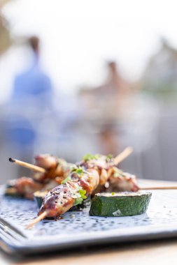 Arka planda dikkati dağınık insanların olduğu bir restoranın masasında, karanlık bir masada servis edilen tuzlu ızgara mürekkep balığının dikey fotoğrafı.