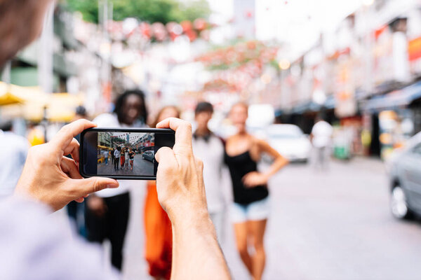 man taking pictures of his friends on the street with his smartphone.