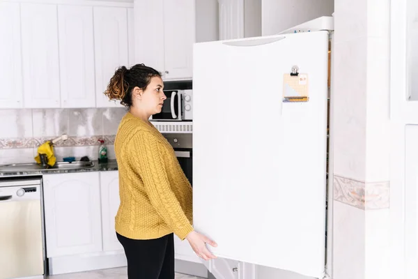 Беременная Женщина Желтом Свитере Смотрит Холодильник Открытой Дверью Кухне Беспокойным — стоковое фото