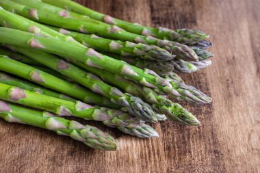 Koyu ahşap masadaki yeşil kuşkonmazın üst görüntüsü, kopya alanı ile yatay olarak.