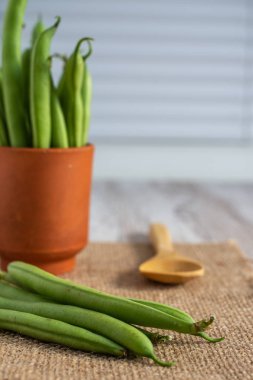 Çuval bezelyeli yeşil fasulye yakın plan, arkaplan fasulyesi kilden kâse ve ahşap kaşık, odaklanmamış beyaz arka plan, dikey