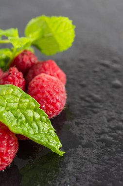 Nane yaprağı ve ıslak ahududu makro üst görünümü odak dışı fotokopi alanı ile dikey siyah sayfaya
