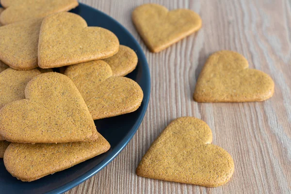 Top view of heart shaped gingerbread cookies, on dark plate and wooden background in horizontal