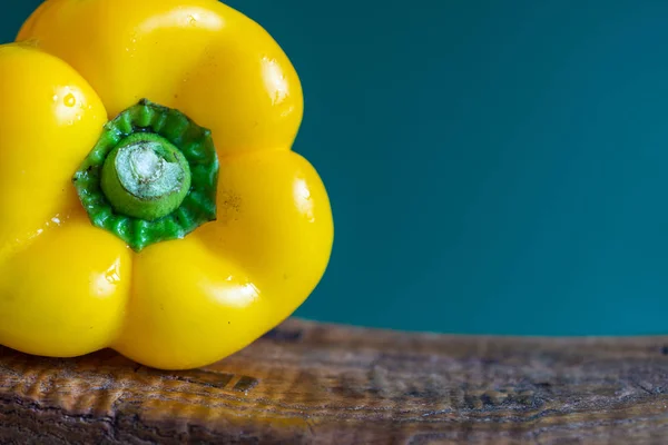 Macro close-up of yellow pepper on a piece of old wood and green background in horizontal with copy space