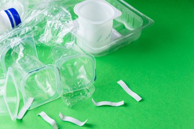 Yeşil zemin üzerinde plastik kapların üst görünümü, geri dönüşüme hazır, kopya alanı ile yatay olarak