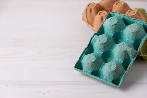 Beyaz ahşap üzerinde yeşil, kahverengi ve sarı altı yumurta için boş kutular üst görünüm, geri dönüşüm için hazırlanmış, yatay olarak kopyalama alanı ile