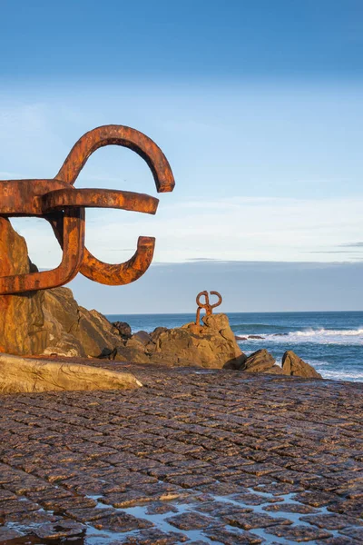 Güneşin doğuşuyla birlikte San Sebastian, Bask Ülkesi, İspanya 'da dikey olarak mavi gökyüzü ile birlikte rüzgarın tarağının heykel setinin görüntüsü