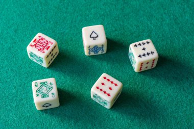 Yeşil hasırda oynanacak beş poker zarının üst görünümü, yatay