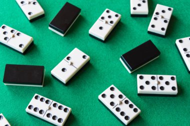 Domino taşlarının üst görünümü, örtülü ve açılır, arka planda odaksız olanlar, yatay oynamak için yeşil minder üzerinde