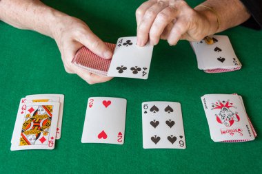 Yeşil paspasın üstünde kadın eli ile poker kartlarının üst görüntüsü. Solitaire, yatay