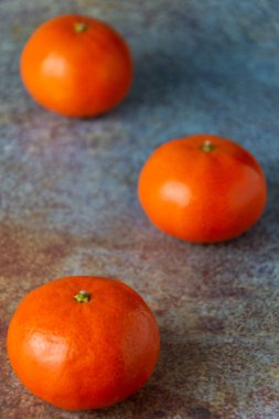 Üç mandalinanın üst görünümü çapraz hizalanmış, seçici odaklı, mavimsi yüzey üzerine