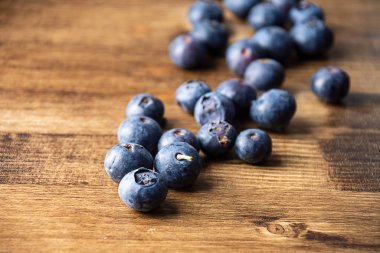 Koyu ahşap tahtada seçici odak noktası yatay ve kopyalama alanı olan bir grup mavi böğürtlenin üst görüntüsü
