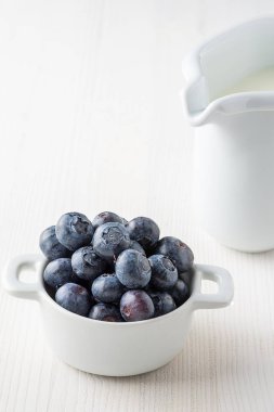 Beyaz fonda yaban mersinli, beyaz arka planda, arka planda odak noktasından çıkmış beyaz sütçü kız var.