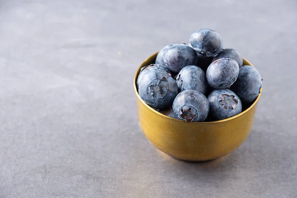 蓝莓在暗色背景下的金碗中与复制空间的特写 — 图库照片