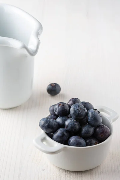 蓝莓在白色碗中的顶部视图 一个在白色背景上 后面是白色的挤奶女工 复制空间 — 图库照片