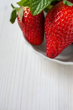 Beyaz arkaplan ve dikey metin için arkaplanda nane aromalı çileklerin yakın plan görüntüsü