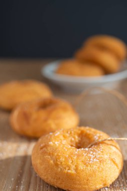 Beyaz tabakta daha fazla donutun bokeh arka planına ve dikey arkaplana sahip çöreklerin yakın plan görüntüsü