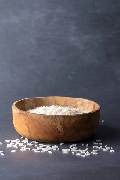 Beyaz pirincin ahşap kasede yakın plan görüntüsü ve dışı, gri arka plan, dikey olarak kopyalama alanı ile.