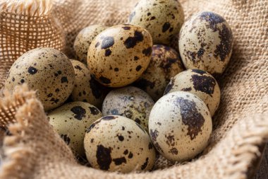 Bıldırcın yumurtalarını çuval bezinin üzerine yakın plan, seçici odak, yatay koyu ahşap masa