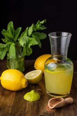 Dilimlenmiş limon suyu sürahisi ve limonlu nane şekeri, dikey arkaplanda bir buket nane ve esmer şeker.