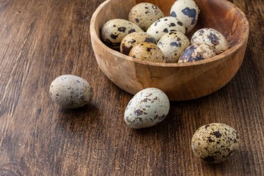 Üzerinde benekli bıldırcın yumurtaları olan ahşap kasenin üst görüntüsü.