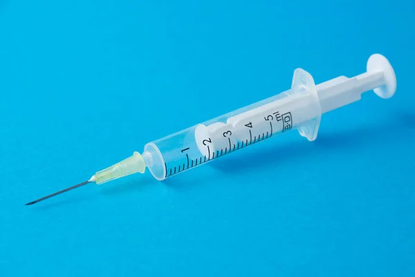 Mavi arkaplandaki şeffaf plastik şırınganın fotokopi alanıyla yatay olarak yakın plan görüntüsü