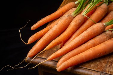 Yeşil yapraklı bir havuç grubunun havadan görünüşü, kırsal bir masada, siyah arka planda, yatay