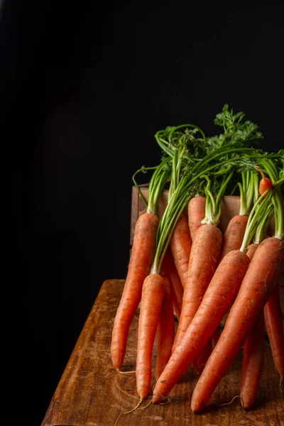 Close Carrots Green Leaves Box Worn Wooden Table Black Background — Stock Photo, Image