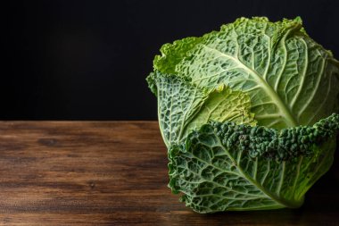Tüm kıvırcık lahanaları koyu ahşap tahtaya yakın plan, siyah arkaplan, fotokopi alanı ile yatay