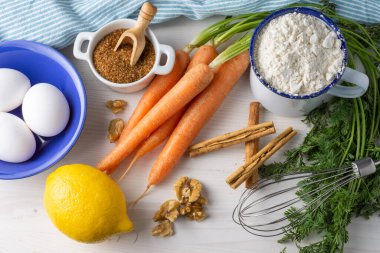 Havuç pandispanyası malzemelerinin havadan görünüşü, beyaz ahşap masa üzerinde, yatay