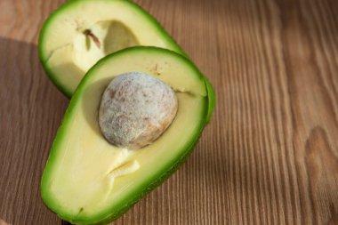 Kesik bir avokadonun üst görüntüsü, ahşap tahta üzerinde, yatay, kopyalama alanı ile