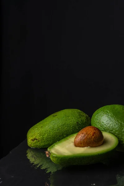 Bovenaanzicht Van Gesneden Groene Avocado Een Hele Natte Zwarte Leisteen — Stockfoto