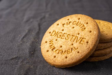 Close-up of digestive biscuits in stack, on dark tablecloth, horizontal, with copy space clipart