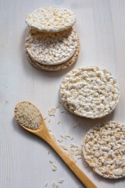 Kilo kaybı ve tahta kaşık için pirinç kreplerinin üst görüntüsü beyaz ahşap masa üzerinde, dikey, fotokopi alanı ile