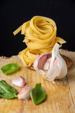 Sarımsak, fesleğen, tagliatelle, seçici odaklı, ahşap masa, siyah arka plan, dikey