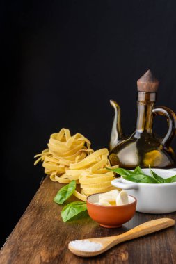 Ahşap kaşığı tuz, sarımsak, fesleğen ve yağ tenekesiyle yakın plan, ahşap masa, siyah arka plan, dikey